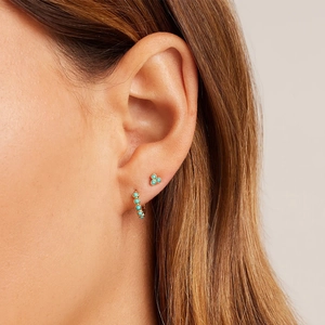Close-up of gold turquoise flower stud and hoop earrings set worn on ear lobe