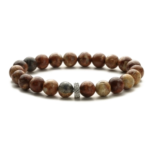 Macro detail of natural tiger eye beads and engraved silver metal spacer on beaded bracelet