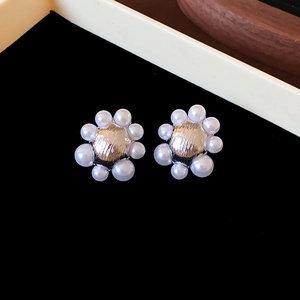 Gros plan détaillé de boucles d'oreilles fleurs dorées avec perles blanches sur velours