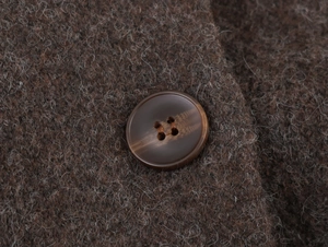 Gros plan sur la texture du manteau en laine marron et détail du bouton premium