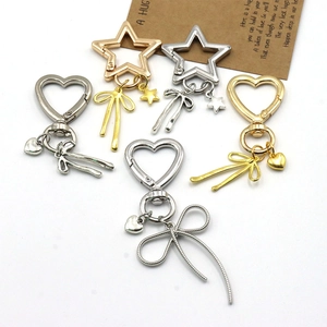 Dettaglio di portachiavi in metallo oro e argento a forma di cuore e stella con fiocco