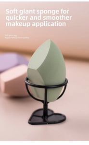 Macro shot of green giant beauty blender with cut edges on a black heart metal stand