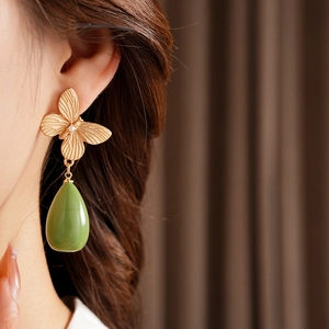 Détail de boucles d'oreilles papillon dorées vintage avec pendentif goutte en résine verte