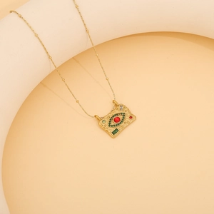 Macro shot of gold tarot pendant with red and green stones on a bead chain necklace