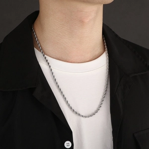 Dettaglio della collana a catena intrecciata argento su un modello in t-shirt bianca