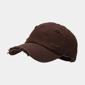 Detailed close-up of the distressed ripped edges on a vintage chocolate brown baseball cap