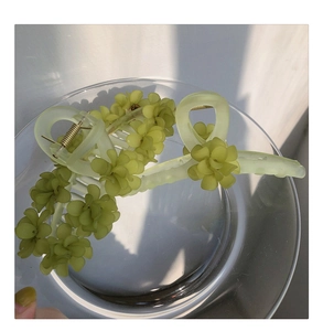 Detail of light green matte flower hair claw clip with tassels on glass tray