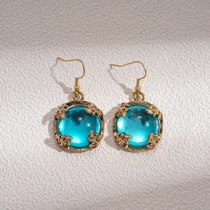 Vue macro des boucles d'oreilles dorées vintage avec grandes pierres en résine bleue