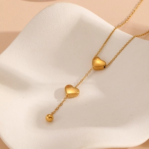 Elegant gold stainless steel necklace with double heart pendants on a white display tray