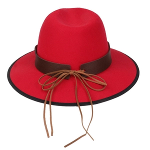 Detailed shot of red wool fedora featuring a brown leather band and thin ribbon bow detail