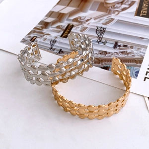 Detail of gold and silver hollow mesh weave bangles on a luxury fashion magazine