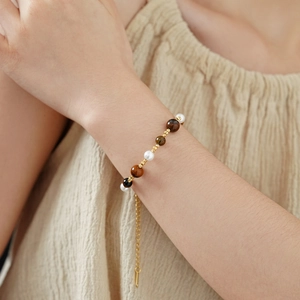 Detail of beaded bracelet with faux tiger eye stones and pearls on model's wrist