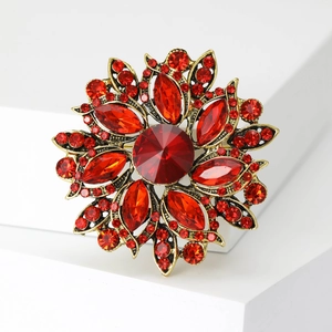 Close-up of vintage floral brooch with large red faceted crystal and antique gold petals