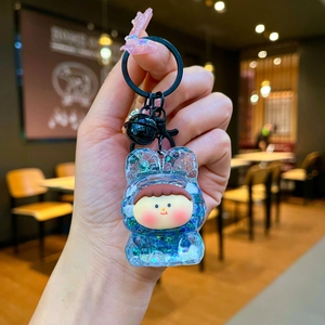 Close-up of a cartoon girl doll inside a blue glitter oil-filled bear keychain charm
