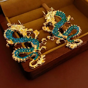 Ear cuff drago dorato con strass turchesi su una scatola per gioielli in velluto