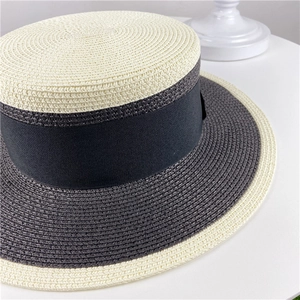 Detailed top view of a two-tone straw boater hat with a black ribbon band and woven texture
