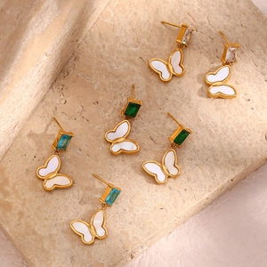 Detailed shot of butterfly earrings with colorful zircon gems on textured stone surface