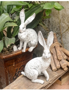 Detail of vintage white resin rabbit garden ornaments set with a rustic stone texture