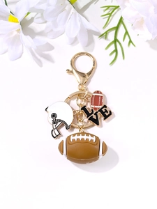 Detail of rugby keychain with brown ball, white helmet and LOVE charm on gold metal ring