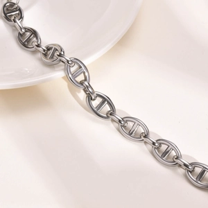 Detailed view of polished silver anchor chain links on a minimalist white ceramic display