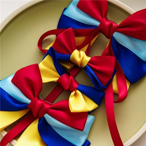 Close-up of four colorful satin ribbon bow hair clips on a beige ceramic plate