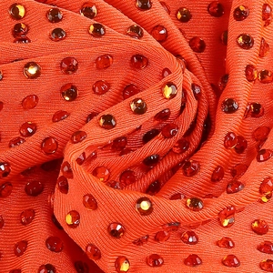 Gros plan d'un tissu tricoté rouge avec strass brillants et texture plissée élégante