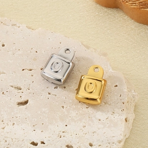 Macro shot of silver and gold square lock charms with letter O on stone base