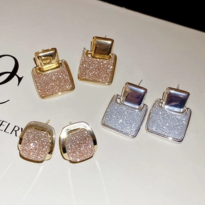 Detail of square 18k gold plated earrings with sparkling glitter inlay in three colors