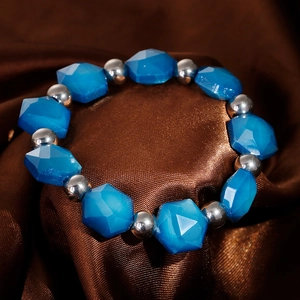 Detail of blue faceted crystal beads and silver steel spheres on brown satin background