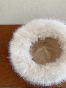 Top view of thick white faux fur bucket hat showing plush texture on wooden table