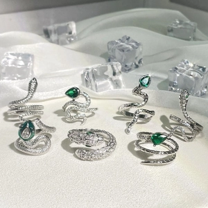 Set of 7 silver punk snake rings with green gemstones on white silk and ice