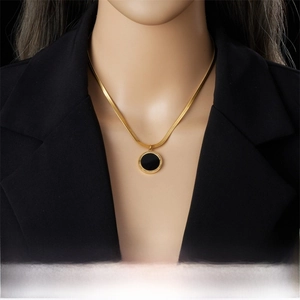 Detail of gold-plated roman numeral pendant on a snake chain shown on a model