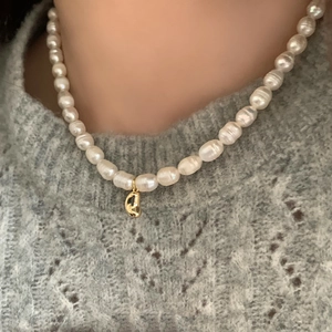 Close-up of a French vintage freshwater pearl necklace with a gold bean-shaped pendant