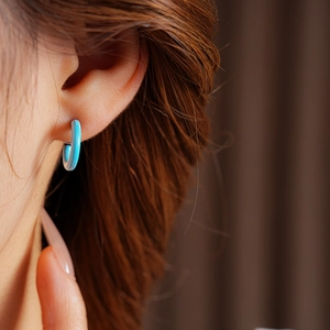 Close-up of light blue enamel C-shaped earrings worn on model for a stylish retro look