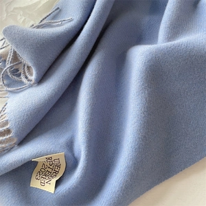 Close-up of light blue cashmere-style scarf with herringbone weave and tassel detail