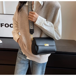 Gros plan sur le sac bandoulière en cuir grainé noir avec large sangle tissée rétro
