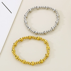 Détail de bracelets en perles d'acier inoxydable or 18 carats et argent sur fond crème