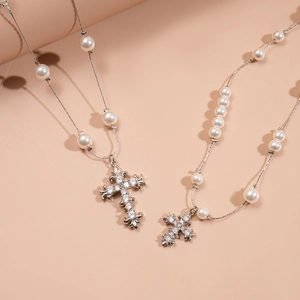 Detail of silver-tone cross necklace with white faux pearls and shimmering zircons
