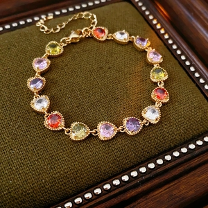 Detail of a vintage gold heart bracelet featuring multicolored zircon stones in a jewelry box