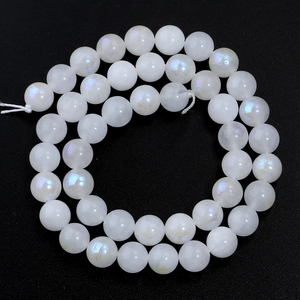 Macro shot of white moonstone beads with iridescent sheen on a black background