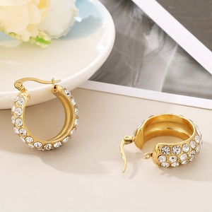 Close-up of elegant gold hoop earrings with sparkling rhinestones on a decorative plate