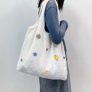 Close-up of white fleece tote bag featuring blue star embroidery and spacious interior
