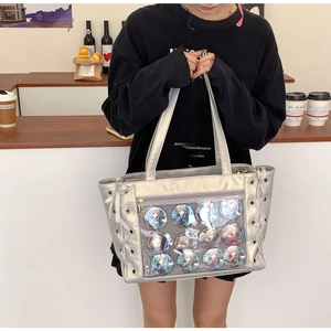 Silver ita bag with clear window displaying twelve anime character badges and white ribbons