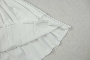 Detailed close-up showing the pleated hem and stitching of this white mini dress