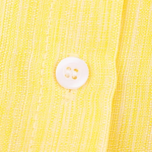 Macro shot of yellow linen dress fabric featuring a white four-hole button detail