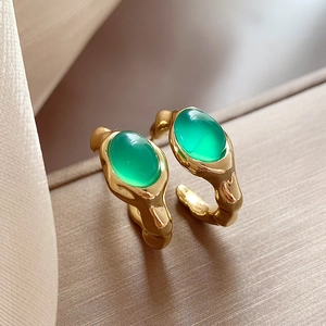 Macro detail of vintage gold enamel earring with a green gemstone and lava texture