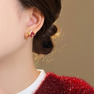 Close-up of golden unicorn stud earring with red enamel and pavé crystals on ear