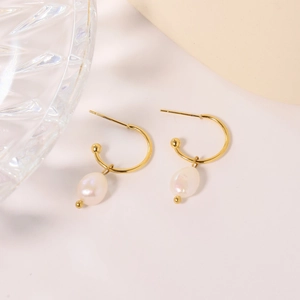 Minimalist gold C-shape hoop earrings with white oval pearls on a soft white background
