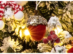 Close-up of red flocked acorn ornament with silver glitter on snowy Christmas tree branch