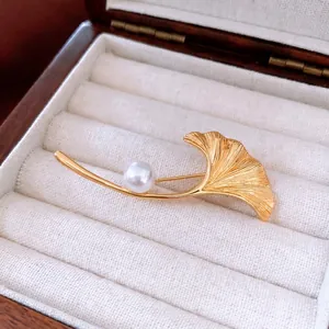 Eleganter 18K vergoldeter Ginkgo-Blatt-Anstecknadel mit Perle auf einer Schmuckschatulle